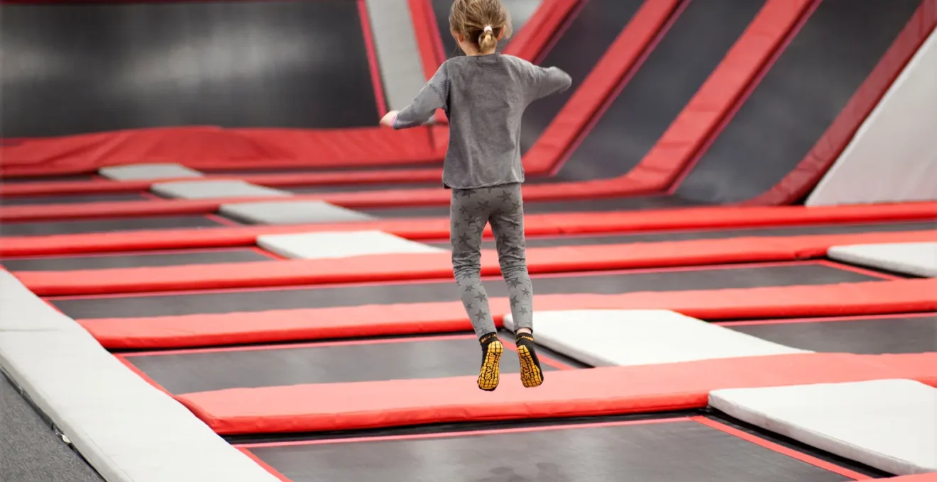 Deux enfants enfilent leurs chaussettes antidérapantes sur un banc près des trampolines.