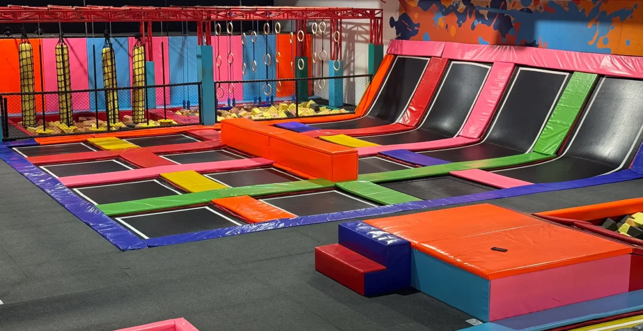 Un parent montre sa réservation sur son smartphone à l'accueil du parc de trampolines.